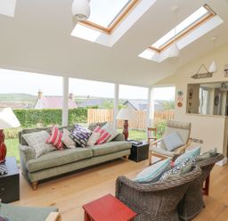 A living room with sofas armchairs side tables and lamps at Tree Tops in Newport Pembrokeshire