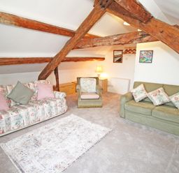 A living room with two sofas and an armchair under exposed wooden beams at Y Stabl The Old Stable in Llanbedr