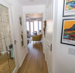 A hallway with wooden floor leading to a living room with chairs and glass doors at Ty Bach Twt Llanelli
