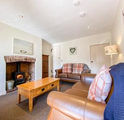 A living room with two leather sofas a wooden coffee table a fireplace and a lamp at Little Dragons in Dunster near Minehead