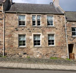 Stone exterior of a building with six windows and a small gate at 49 Castlegate in Jedburgh
