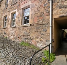 A stone building with windows and a passageway alongside a cobblestone path at 49 Castlegate in Jedburgh