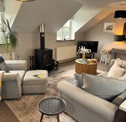 A living room with seating and a stove at The Hayloft in Lostwithiel
