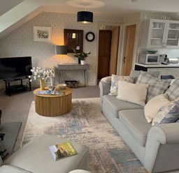 A living room with a sofa, coffee table, and television at The Hayloft in Lostwithiel
