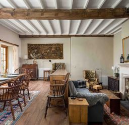 A living room and dining area with wooden furniture and a fireplace at Courtyard House in Blockley