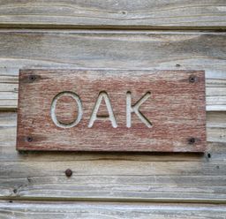 A wooden sign with the word OAK carved on a wooden wall at Oak Lodge in Rosliston