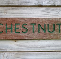 A wooden sign with the word chestnut mounted on a wooden wall at Chestnut Lodge in Rosliston