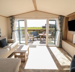 A living room with a sliding door leading to the deck at Fir Lodge in Whitby
