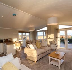A living room with sofas a coffee table dining area and kitchen at Cherry Blossom Lodge in Whitby