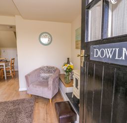 An open black door showing a living area with a single armchair and a dining table in the background at Dowlais in Llanllyfni near Penygroes
