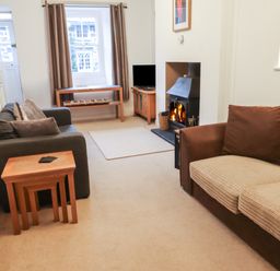 A living room with two sofas a fireplace a wooden table and a small television at Ty Glyn in Beddgelert