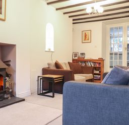 A living room with a fireplace two sofas a wooden bookshelf and glass double doors at Ty Glyn in Beddgelert
