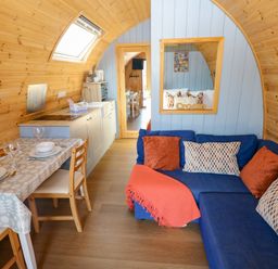 A living room with a sofa and dining area at Ty Twt Teifi in Llanddewi-Brefi