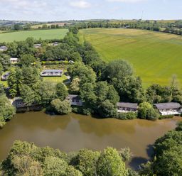 An aerial view of a lake surrounded by trees and houses at 1 Miller's Island near Lanreath