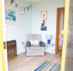 A small sitting area with an armchair a side table with a lamp a fireplace and wall art at Homestead Aberdesach near Penygroes