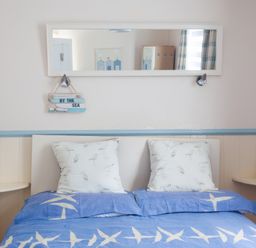 A bedroom with a double bed blue bedding white pillows wall mirror and small shelves at Homestead in Aberdesach near Penygroes