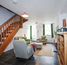 A living room with gray armchairs a wooden staircase and a wooden shelf at Quarrymans cottage in Beddgelert