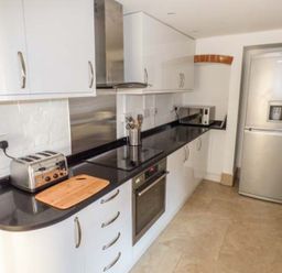 A kitchen with white cabinets black countertop stove toaster microwave and silver refrigerator at 1 Willow Cottage in Upton Upon Severn
