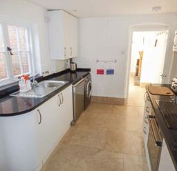 A kitchen with white cabinets black countertops a sink window and appliances at 1 Willow Cottage in Upton Upon Severn