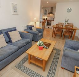 A living room with blue sofas and a wooden coffee table next to a dining table and kitchen at Pierpont D1 Norton near Yarmouth