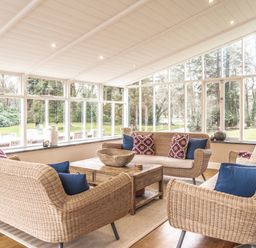 A conservatory with wicker furniture and a coffee table at Tan Llan Llanelltyd near Dolgellau
