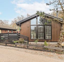 A wooden cabin with large windows and a path at Fig Tree Lodge in Hutton Roof near Penrith