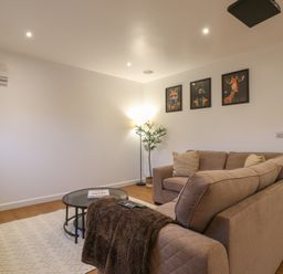 A living room with a brown sofa coffee table floor lamp and three animal portraits on the wall at Hub House in Three Oaks near Hastings