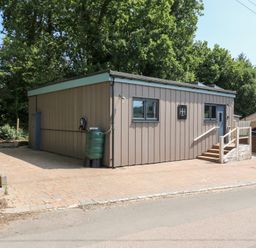 An outdoor view of a building with steps and a rainwater tank at Hub House in Three Oaks near Hastings