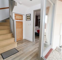 A hallway with a staircase and door to a bedroom at Coastguard Lookout in Wyke Regis