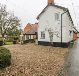 A house with a gravel driveway and trees at White Gates in Banham