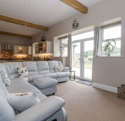 A living room with a sectional sofa and kitchen in The Gatehouse 