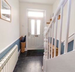 A hallway with a staircase and front door at Dinguardi in Seahouses