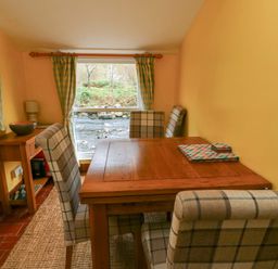 A dining room with a table and chairs at Riverbank Cottage in Beddgelert