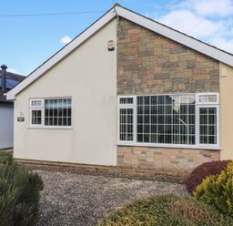 The exterior of a house with two windows a stone and plaster wall and shrubs in the front garden at Samson's Place in Morfa Bychan