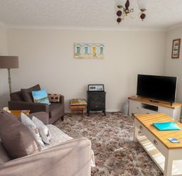 A living room with sofas a television on a stand a coffee table and a floor lamp at Samsons Place in Morfa Bychan