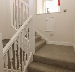A staircase with a handrail and light switch at 21A High Street Jedburgh
