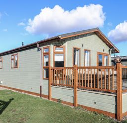 A single-story house with wooden framed windows and a wooden deck with glass panels at Stones Throw in Marston near Barkston