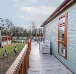 A wooden deck with a bench and table set outside a building near a pond with ducks at Stones Throw in Marston near Barkston