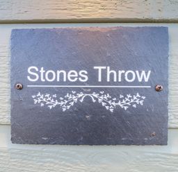 A stone sign with the text Stones Throw mounted on a light colored wooden wall at Stones Throw in Marston near Barkston