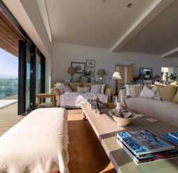 A living room with sofas cushions coffee table and glass doors overlooking a coastal view at Oystercatcher in Mevagissey