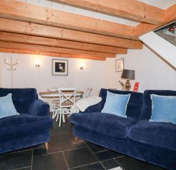 A living room with blue sofas and light wood ceiling beams at 2 Rose Cottage in St Agnes