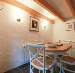 A dining room with wooden table and four chairs with wooden beams on ceiling at 2 Rose Cottage in St Agnes