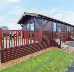 An exterior view of a wooden cabin with a deck and outdoor seating at Cuckoo in Ramsey Huntingdon
