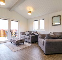 A living room with two gray sofas a matching ottoman and a small table near a window at Cuckoo in Ramsey Huntingdon