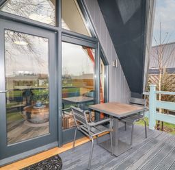 A small outdoor balcony with a table and two chairs in front of glass doors at Sunflower Lodge Near Misterton
