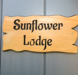 A wooden sign with Sunflower Lodge text mounted on a gray door at Sunflower Lodge Near Misterton
