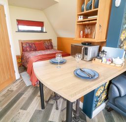 A small room with a bed dining table microwave and sofa at Sunflower Lodge Near Misterton