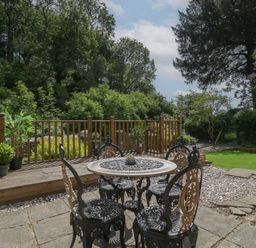 A garden with a table and chairs at Court House Cottage in Gatcombe near Blakeney