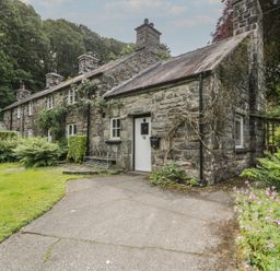 A stone house with a garden and pathway at Glandwr Cottage in Llanbedr