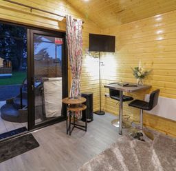 An interior room with wooden walls a small table with two chairs a wall mounted television and sliding glass door at Binevanagh Cabin Magilligan near Castlerock